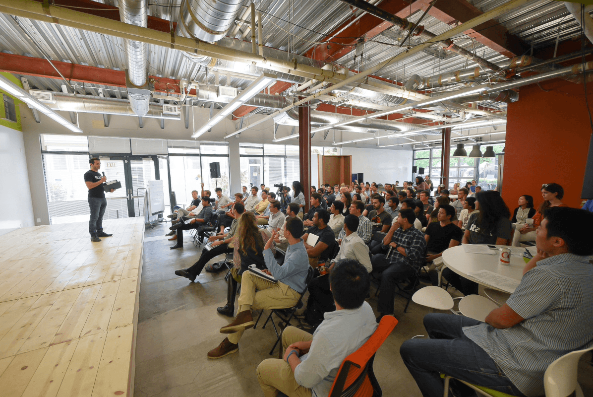 Startup scouting through university partnerships and technology transfer programs, featuring an academic event connecting researchers and entrepreneurs.