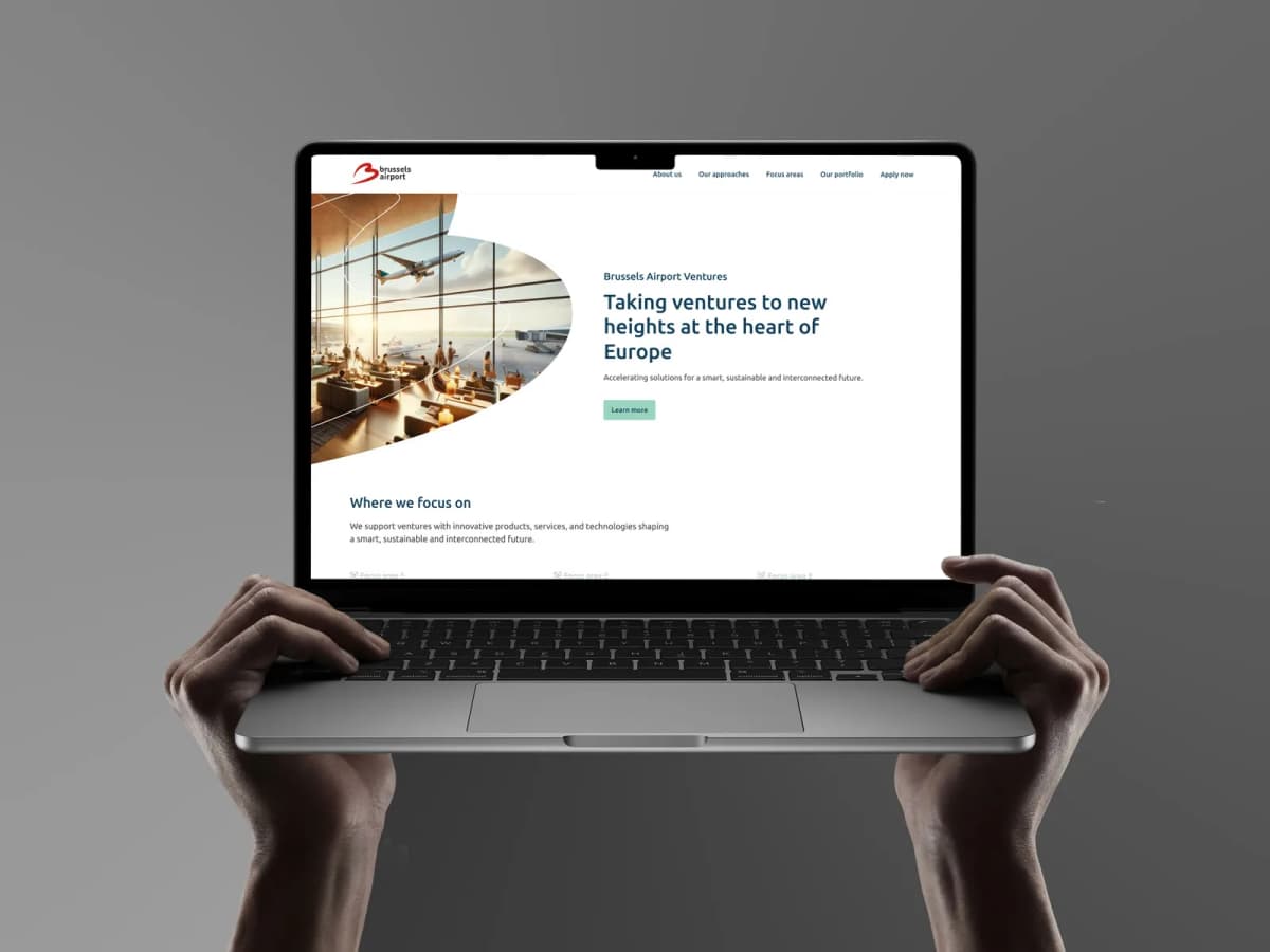 Hands holding a laptop that shows the Brussels Airport Ventures website: Taking ventures to new heights at the heart of Europe