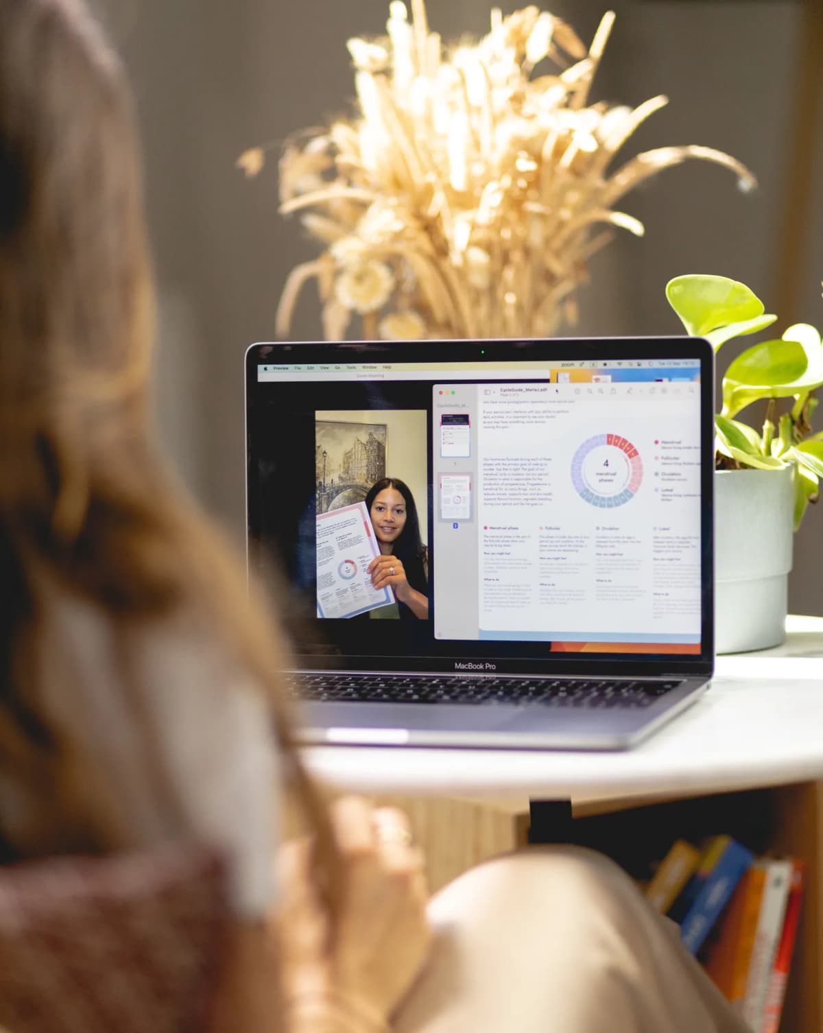 A customer on a video call with a Monthlies nutrition coach, her cycle plan on the laptop screen