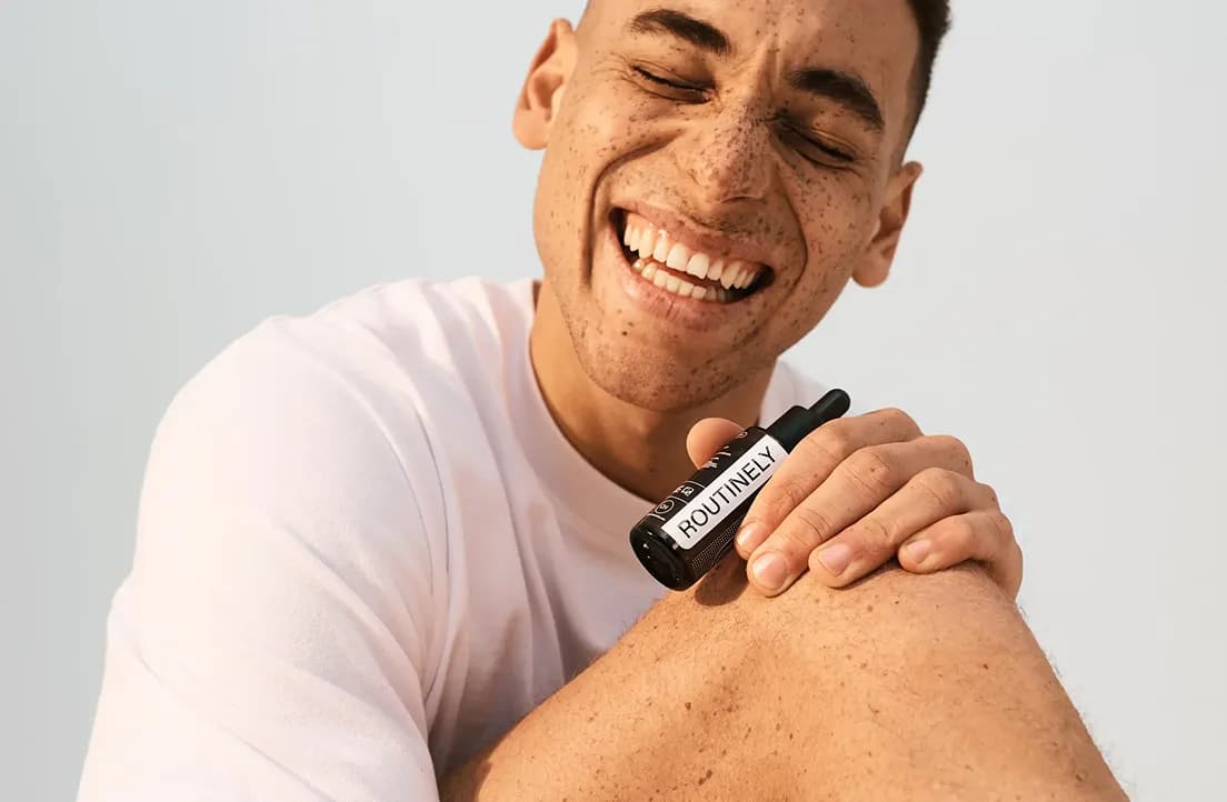 A smiling man applying Routinely serum to his knee